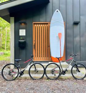 two bikes parked in front of a house with a surfboard at SEVEN TREES BY AOKIKO in Omachi