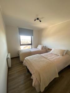 two beds in a room with a window at Excepcional Depto Puerto Varas in Puerto Varas