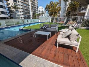 a patio with couches and a table next to a pool at Beach and Breeze in Mooloolaba