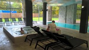 Eine Frau steht in einem Pool mit zwei Leuten im Wasser. in der Unterkunft Diune Resort & Apartamenty in Kołobrzeg