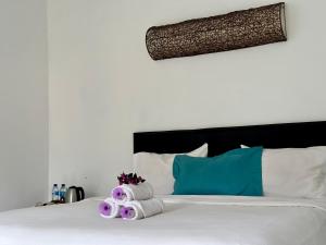 a white bed with purple and blue pillows at The Winaposa in Munduk