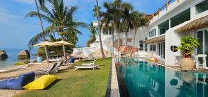 a house with a swimming pool next to the ocean at The Rock Samui Beachfront Resort - Sha Plus Hotel in Lamai