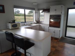 a kitchen with a counter and two chairs in it at Arawai - Waimarama Holiday Home in Waimarama
