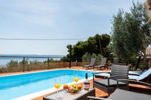 a pool with a table with wine glasses and a bowl of fruit at Angeli Del Mare in Marusici 