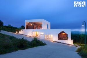 马迪凯里StayVista at Reflection by The Woods - Breakfast Included - Luxury Villa的白色的房子,晚上有灯光的外墙