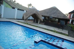 a house with a thatch roof and a swimming pool at CHAMBO VILLAS in Morogoro