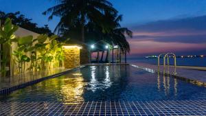 a swimming pool with a view of the ocean at night at The Bay PD Beachfront Villa in Port Dickson