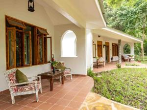 a porch of a house with chairs and a table at Mount Meru Game Lodge & Sanctuary in Arusha