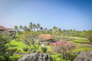 un giardino con fiori e alberi e una casa di Newly Renovated Condo with SUP Paddle Boards and Golf Clubs Included a Kailua-Kona