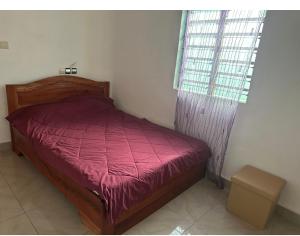 ein Schlafzimmer mit einem roten Bett und einem Fenster in der Unterkunft Maison de vacances Calavi séminaire in Abomey-Calavi