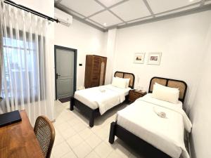 um quarto de hotel com duas camas e uma mesa em CERIA HOTEL at Alun Alun Yogyakarta em Yogyakarta