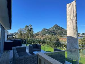 a deck with chairs and a view of a mountain at Ocean Beach Paradise in Tairua