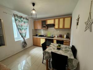 a kitchen with a table and chairs and a kitchen with a table and a table at Apartmani Luciano in Novalja