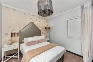 a white bedroom with a bed and a chandelier at The Icon Capetown in Cape Town +20 photos