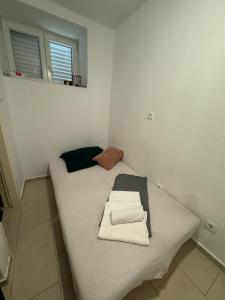 a small room with a bed with two towels on it at Apartmani Luciano in Novalja
