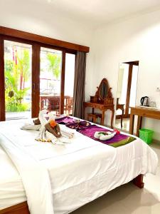 a bedroom with a large white bed with a stuffed animal on it at Pererenan nengah guest house in Canggu