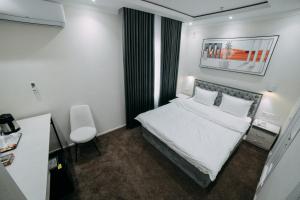 a hotel room with a white bed and a chair at Central Plaza Hotel in Urganch