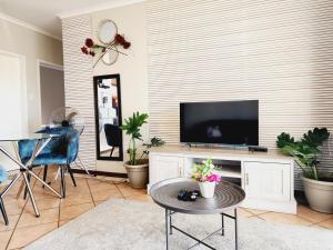 Una sala de estar con un televisor y una mesa. en Sable woods, en Pretoria