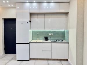 a kitchen with white cabinets and a sink at Green City Apartment in Tbilisi City