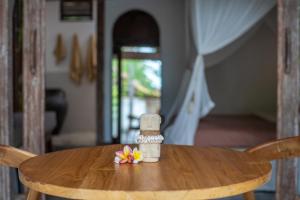 a small bottle on a wooden table with flowers on it at Akasia Villas - Private Pool Villas in Gili Islands