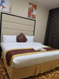 - une chambre avec un grand lit et une grande tête de lit dans l'établissement Al Massa Hotel Apartments 1, à Al-Aïn