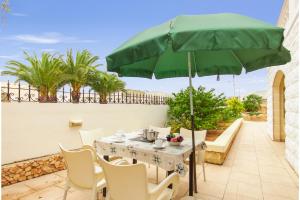 Una mesa con una sombrilla verde en un patio. en Villa & Pool Apartments in Mellieha Bay, en Mellieħa