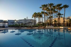 ein großer Swimmingpool mit Palmen und Sonnenschirmen in der Unterkunft Delfina Tropic Beach - Adults Only in Georgioupoli