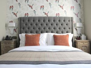 a bed with a large headboard and two night stands at The One Tun Pub & Rooms in London