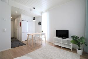 a white living room with a table and a tv at Forenom Serviced Apartments Kirkkonummi in Helsinki