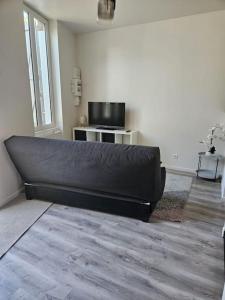 a black couch in a living room with a television at Beautiful F2 apartment 5 stops by train from Paris in Moret-sur-Loing +14 photos