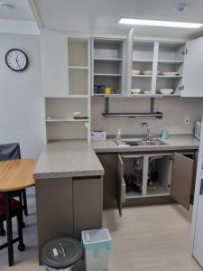 eine Küche mit weißen Schränken und einem Waschbecken und einem Tisch in der Unterkunft Sokcho Koaroo Arista in Sokcho