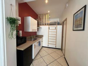 a small kitchen with red walls and white cabinets at Studio 2 personnes Béthune Centre in Béthune
