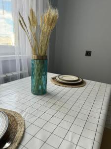 a white tiled table with a vase with grass at Современная квартира в Алматы для 4 человек in Shugyla