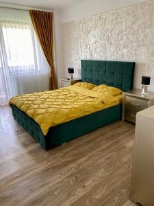 een slaapkamer met een groot bed met een groen hoofdeinde bij Sofia Residence Apartments in Tîrgu Neamţ