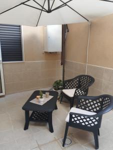 Un patio con dos sillas y una mesa y una sombrilla. en Kitros, en Palagiano