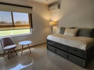 ein Schlafzimmer mit einem Bett und einem Stuhl und einem Fenster in der Unterkunft Amplitud y Confort al Sur de Guadalajara in Los Gavilanes