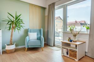 a living room with a blue chair and a potted plant at Apartamenty Lighthouse - Premium Dźwirzyno in Dźwirzyno