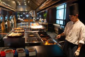 a man cooking food on a grill in a kitchen at Tower Club at lebua in Bangkok
