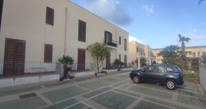 un'auto parcheggiata in un parcheggio accanto a un edificio di holiday home LG a San Vito lo Capo