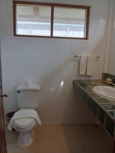 a white bathroom with a toilet and a sink at Pinnacle Samui Resort in Mae Nam