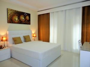 een witte slaapkamer met een wit bed en een schilderij bij São Francisco Accommodation in Funchal