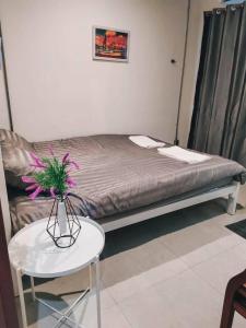 a room with a bed and a table with a vase with flowers at Jira19Hostel in Bangkok