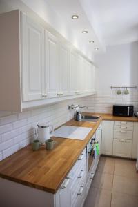Una cocina con gabinetes blancos y una encimera de madera. en Strzelecka Old Town Apartament, en Gdansk