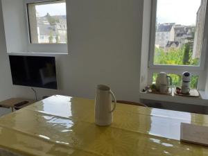 a coffee cup on a table in a room with two windows at Havre de paix in Rodez