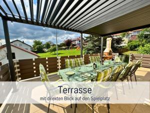 a patio with a long table with yellow chairs at Nur 15 Minuten bis Fulda - ideal zum Arbeiten - Am Vulkanradweg - 3 Schlafzimmer Große Terrasse - Grill - Ferienhaus Taufstein 1 in Herbstein