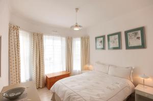 a bedroom with a bed and two windows at Mermaid Rock Cottage in Cape Town +21 photos