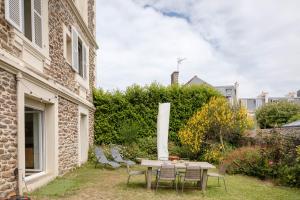 einen Tisch und Stühle in einem Hof neben einem Gebäude in der Unterkunft Bagatelle - Appt à 300 m de la plage in Dinard