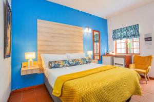 a blue bedroom with a bed with a yellow blanket at The Villa Manor & Spa in Bela-Bela