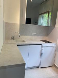 een witte keuken met een wastafel en een spiegel bij Apartments & Rooms Bianca in Mali Lošinj +75 foto's