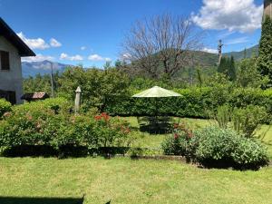 a table and an umbrella in a garden with flowers at La Ca del Bicc in Luino +7 photos